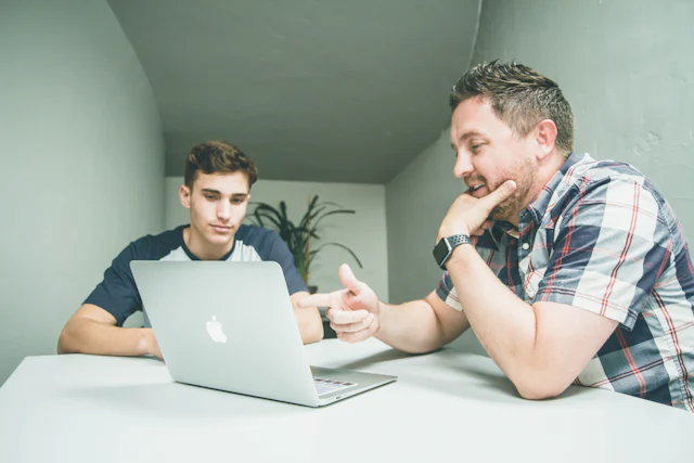 A mentor reviewing work with a learner on a laptop