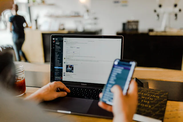 A marketer checking ad results on a phone and laptop